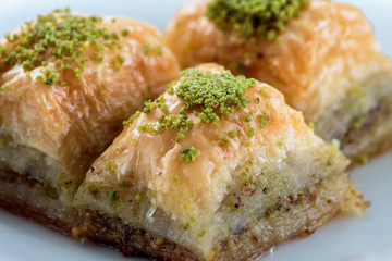 Baklava with pistachios and walnuts on white plate close up. Shallow depth of field