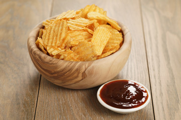 rippled potato chips with paprika and bbq sauce in wooden bowl, with copy space