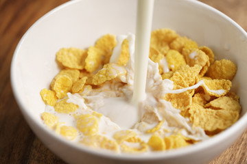 milk pour into bowl with corn flakes, preparing breakfast