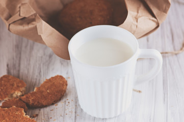 Mug with milk and oatmeal cookies wrapped in paper edge