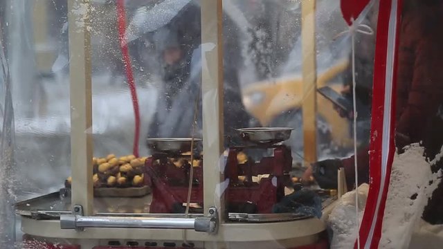 a man selling chestnut in winterday while snowing