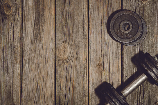 Old Iron Dumbbells Or Exercise Weights Outdoor On An Old Wooden Deck, Floor Or Table In The Gym. Image Frame Taken From Above, Top View. A Lot Of Copy Space Around Product