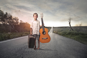 Child with guitar in the middle of the road