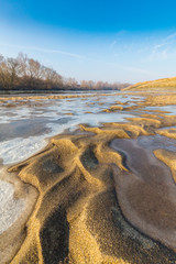 Winter scenery, with frozen river and ice covered sand dunes, on a cold sunny day