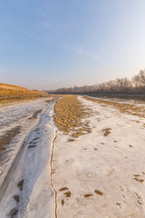 Winter scenery, with frozen river and ice covered sand dunes, on a cold sunny day