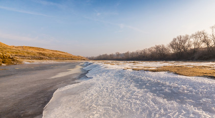 Fototapeta na wymiar Winter scenery, with frozen river and ice covered sand dunes, on a cold sunny day
