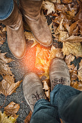 Feet in shoes on the autumn leaves. Relationship in a pair of lovers.