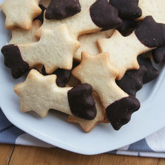 Biscotti al burro a forma di stella su piatto su tavolo di legno
