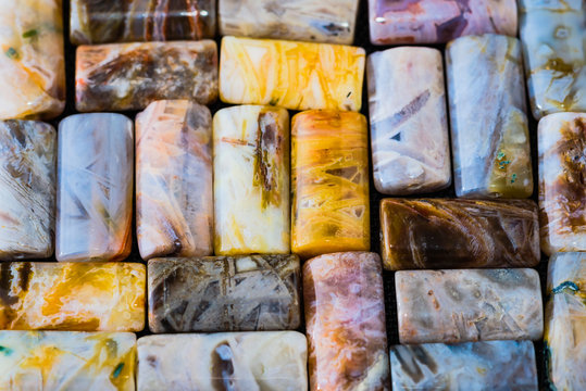 Collection of shiny rectangular agate beads background on black weave.