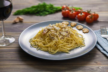 Spaghetti Carbonara with ham and mushrooms in blue plate on wooden table