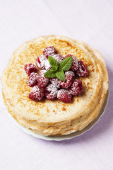 Stack of Russian-style pancakes with raspberries