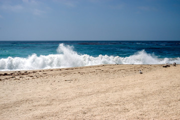 Strand mit Wellen die brechen und Sand