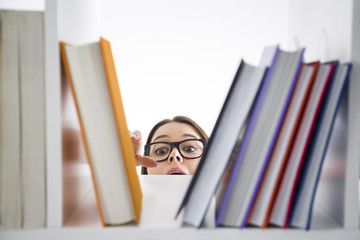 Young girl in glasses reaching for a book