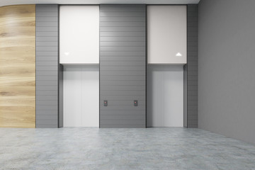 Two white elevators in office, gray walls