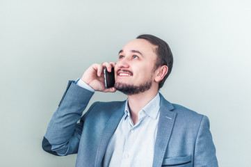 Man talking on the phone, looks up and smiles. Businessman happy about the good news