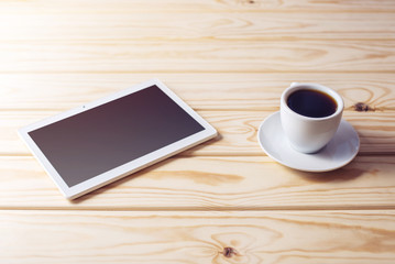 Fototapeta na wymiar digital tablet lying on wooden table and cup of coffee