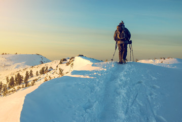 man hiker going in the mountains through the snow