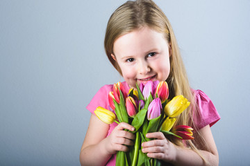 Smiling blond girl with a bouquet of tulips.