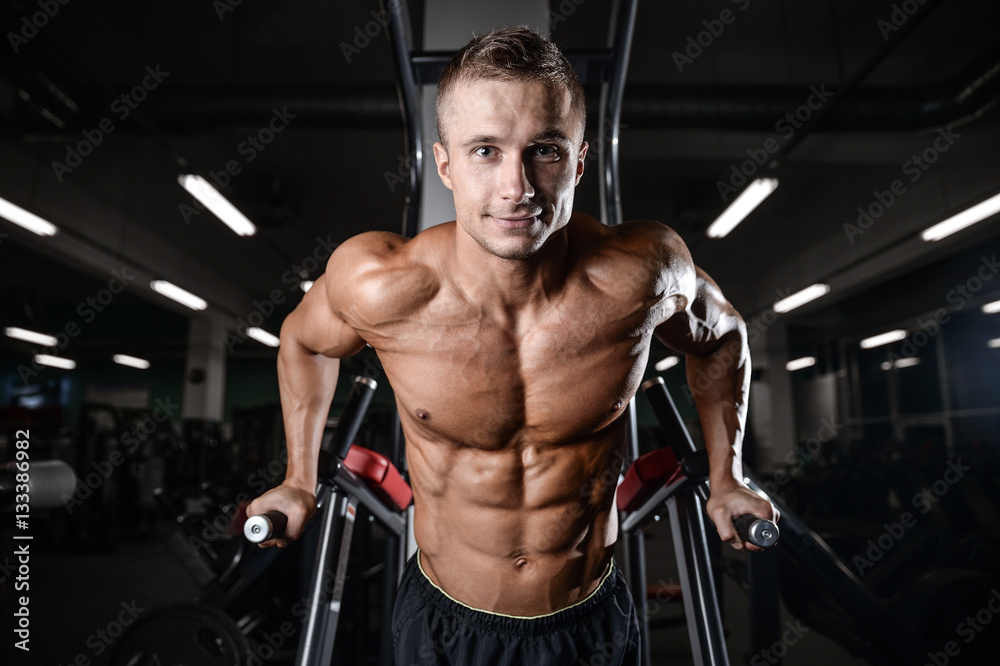 Wall mural Handsome fitness model train in the gym gain muscle