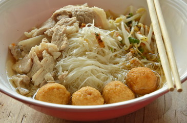 rice vermicelli topping shrimp ball and slice boiled pork in soup eat by wooden chopstick