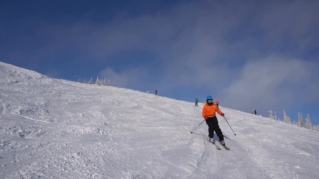 Woman skier is going down from mountain's top at sunny frosty day