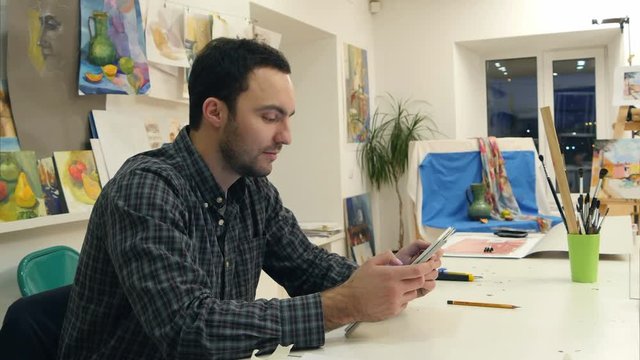 Male painter using digital tablet in art workshop