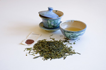 Cup of tea, tea leaves, scattered pile on a white background