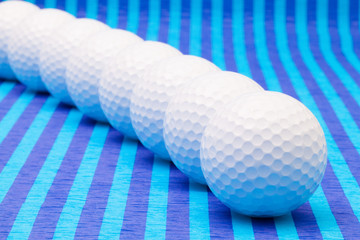 White golf balls on blue striped table.