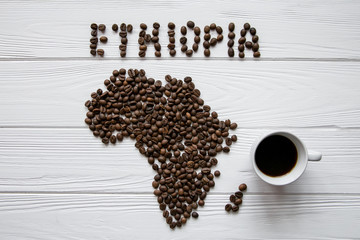 Map of the Ethiopia made of roasted coffee beans laying on white wooden textured background with coffee cup and space for text