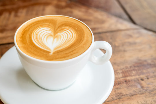 Fototapeta Close up white coffee cup with heart shape latte art on wood tab