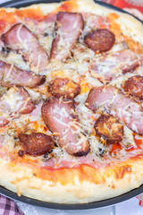 Flat lay overview of pizza with domestic ham sirloin and sausage