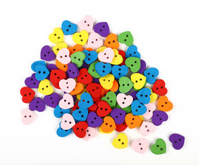 Colorful heart shaped sewing buttons over white