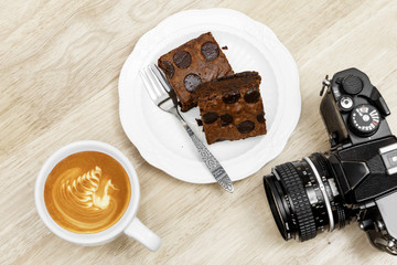 Chocolate brownie coffee latte break and vintage camera on woode