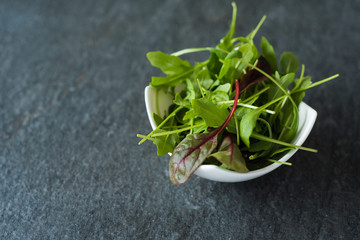 Obraz na płótnie Canvas light salad of leaves of mangold ruccola spinach on stone