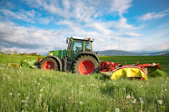 Heuernte - Traktor mäht Gras auf einer Wiese im Allgäu
