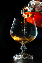 Cognac is poured from a bottle into  glass