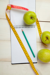 Green apples with measuring tape on a white wooden table