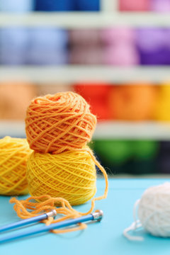 Knitting yarn and needles on blue table against blurred background. 