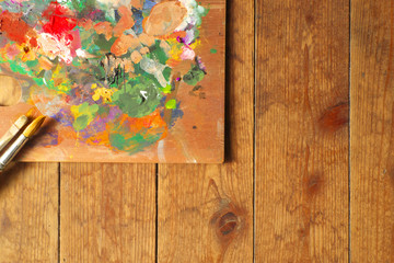 Palette and paintbrushes on wood background