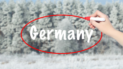 Woman Hand Writing Germany with a marker over winter forest.