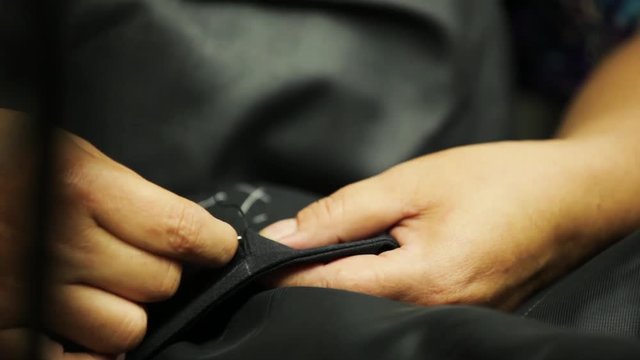 Sewing a button onto a bespoke tailored suit
