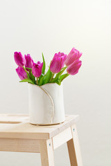 Beautiful Fresh Spring lila Tulips in Vase on Wooden Stool. Spri