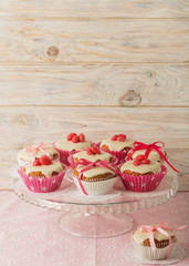 Cupcakes with white icing decorated with pink candy and ribbons.