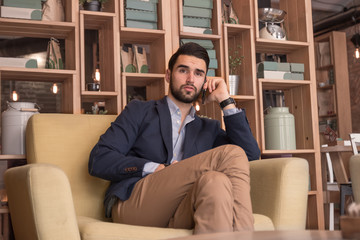 Fototapeta premium young adult man listening phone sitting indoors cafe interior