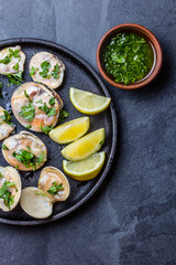 Raw clams with lemon, herbs and white wine, slate background