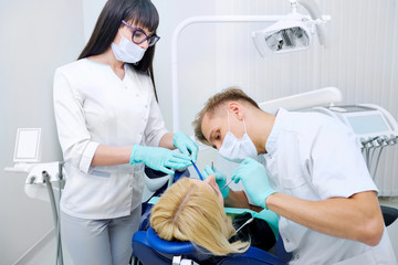 Obraz premium Dentist man with assistant treats teeth patient in hospital office