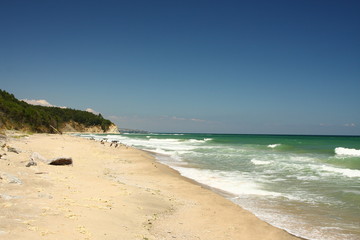 Beautiful sunny beach with blue sky, white waves and golden sand on the Black sea