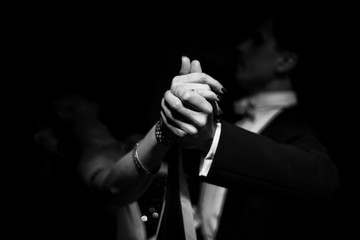 Fototapeta couple dancing on a dark background. focus on hands obraz