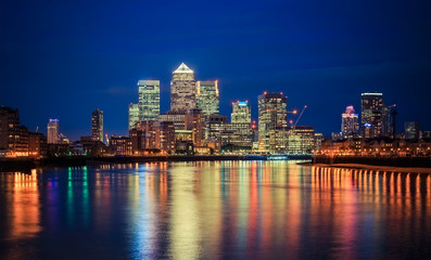 Canary Wharf business district in London at night over Thames River. - obrazy, fototapety, plakaty