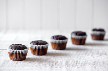 Chocolate muffins on a white rustic wooden table - selective foc